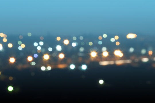 Defocused or blurred image of multi-colored lights in the city streets. Abstract background, selective focus.