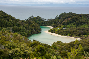 Fototapeta na wymiar An inlet with blue sea, white sand and green trees in the Abel Tasman National Park, New Zealand