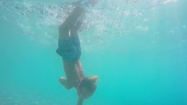 Little boy swims in the Mediterranean sea under water. The boy dives into the blue sea. Mediterranean sea. Clean beautiful sea. 7 years old boy is diving. Real time.