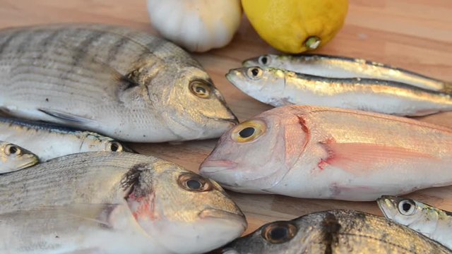 Raw fish. Fresh fish with lemon ready for cooking. Preparing delicious and tasty seafood meal. Uncooked Gilt-head sea bream, Sardines, Common pandora, top view. Healthy food concept. Cooking dinner