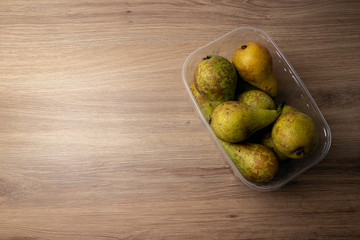 Container with pears on a wooden table
