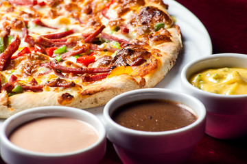 Delicious pizza with with sauces on the table. Food concept