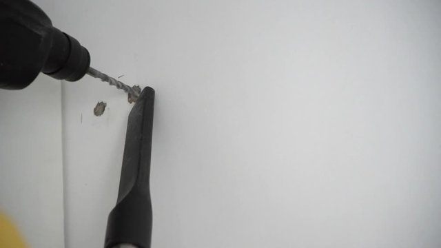 A Builder drills a hole in the wall