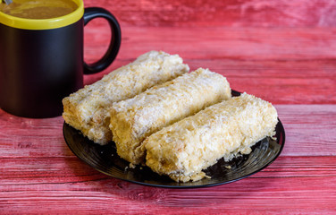 Napoleon cakes a cup of coffee on a red wooden background.
