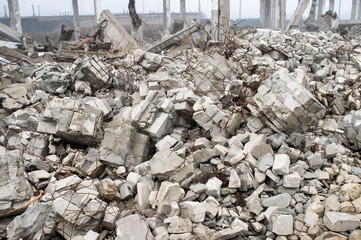 The remains of a large concrete building in the form of fragments of piles and piles of stones.