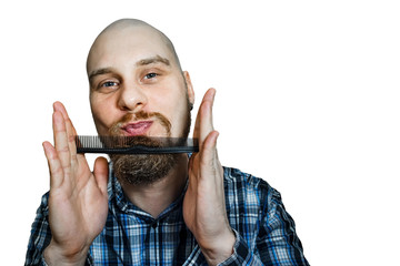 Bald funny guy with a beard and a comb in his hands, combing his head and beard in the morning at...
