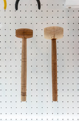 Wood hammers hanging against white dot wall background.