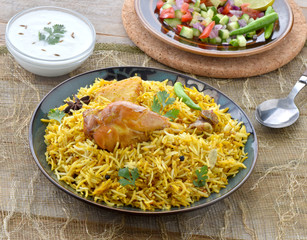 Chicken Biryani, a deleciously colorful rice dish filled with spicy marinated chicken  along with salad & raita.
