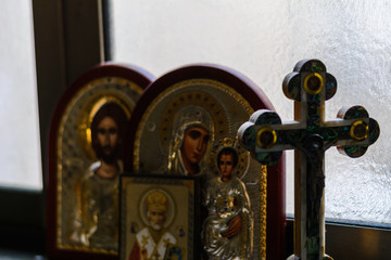 christian cross and icon of the Blessed Mother of God with baby Jesus and icon of Jesus Christ on the window in the house