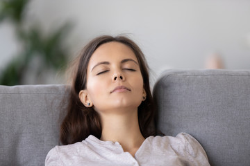 Naklejka premium Calm young woman relaxing on comfortable sofa with closed eyes close up