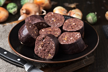 cut raw blood sausage and vegetables on wood