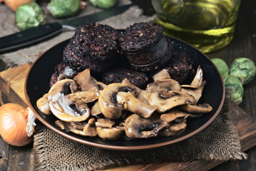 sliced mushrooms and blood sausage, fried in a porcelain dish on wood