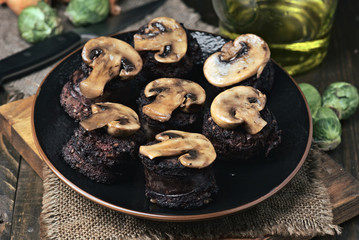 sliced mushrooms and blood sausage, fried in a porcelain dish on wood
