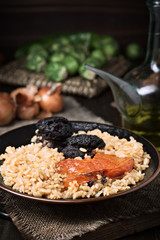 Homemade rice stew with black pudding and tomato in porcelain dish on wood