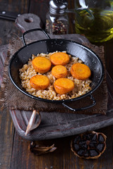 serving of rice stew with carrots, in metal frying pan on wood