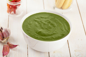 Green cream soup of spinach and chickpeas on concrete wood background