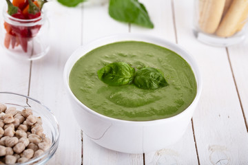 Green cream soup of spinach and chickpeas on concrete wood background