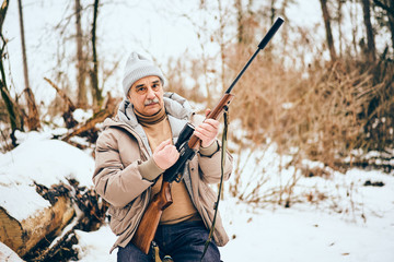 Fototapeta premium Senior man sitting in a personal lumber yard with a rifle
