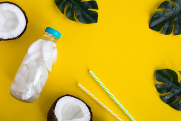 Detox water with coconut in the glass bottle  on the yellow  background.Top view.Copy space.