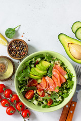 Diet menu concept. Summer Healthy salad with quinoa, Tomatoes, Salmon, Avocado and arugula. Top view flat lay background on light stone table with copy space.