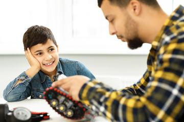 Young boy and his father building a robot together