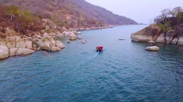 Aerial over a small dive tour boat filled with tourists off the coast of Monkey Bay, Malawi.