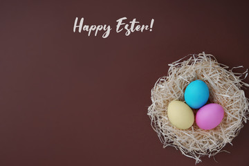 Fototapeta na wymiar Happy Easter greeting card; Colored eggs in a hen nest.