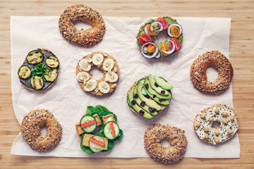 Stylish and tasty composition of vegan bagels sandwiches with vegetables, herbs, paste, seeds, hummus and lettuce on the brown wooden table. Fresh and healthy breakfast. Body balance. Lifestyle.