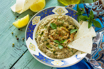 Arabic cuisine. Fresh homemade creamy mung hummus with spicy, falafel, sour cream sauce on a wooden kitchen table. Ramadan food. Copy space.