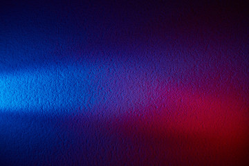 On a blue textural background, a beam of white light and a red volume spot