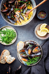 Traditional barbecue Italian blue mussel in white wine creme sauce with salicornia and baguette as top view in a casserole