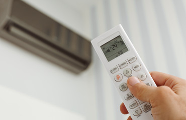 Close up of male hand holding remote control for the air conditioning with copy space