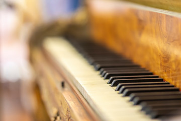 Piano keys with a high depth of field and a nice bokeh on the wooden brown classical piano. An old aged musical instrument keep it in good conditions for playing awe music
