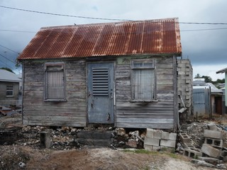 Small dilapidated wooden house with rusty roofs in a community