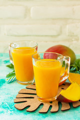 Concept of vegetarian food, fresh vitamins. Refreshing summer mango and citrus freshly squeezed juice on stone table. Copy space.