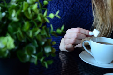 The girl puts a cube of sugar in coffee
