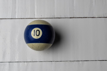 Old billiard ball number 10 striped white and blue on white wooden table background, copy space