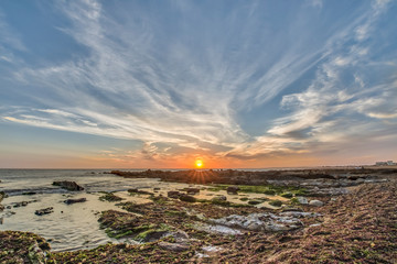 Uruguayan wild lonely beaches and idyllic sea landscapes at Uruguay coastline. Here we can see sunset at  Cabo Polonio beach, the sun goes down behind the rocks above the water horizon over the sea