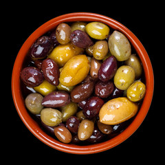 green and purple, mixed olives in clay bowl - isolated on black background