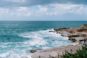 view of the sea and rocky coast strewn with stones. Windy weather and waves break on the shore