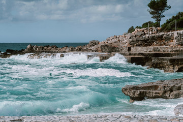 view of the sea and rocky coast strewn with stones. Windy weather and waves break on the shore