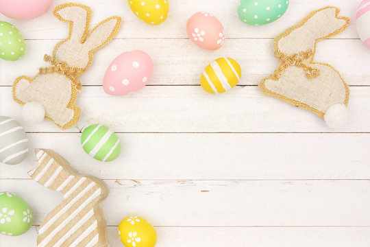 Rustic Easter corner border with burlap bunnies and Easter Eggs against a white wood background. Copy space.