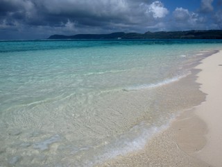 Beautiful white sand beach with clear waves breaking gently on the shore in a tropical island