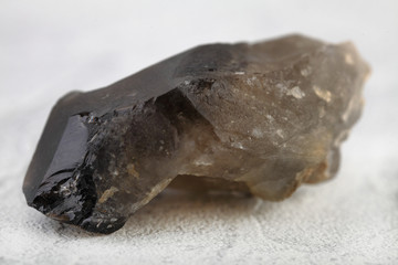 Close-up of smoky quartz stone from Ural region, Russia on white cement background. Rauchtopaz crystal on white background.