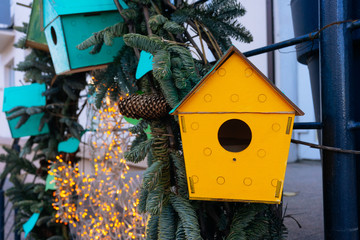 Yellow wooden colorful bird feeders on the tree. Eco (natural) house.