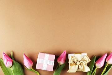 Fresh flower composition, bouquet of bi color pink tulips, brown paper background with present. International Women's day, mother's day greeting concept. Copy space, close up, top view, flat lay.