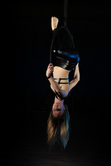 gymnast girl aerial acrobatics on the ring on the background of blue smoke in the dark