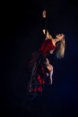 gymnast girl aerial acrobatics on the ring on the background of blue smoke in the dark
