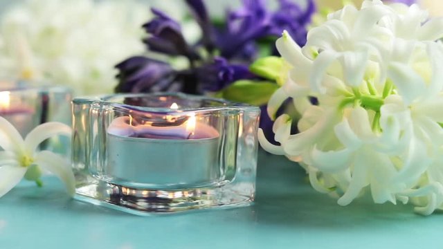 Greeting card with blue candles in front of white and blue hyacinths over blue concrete surface background. Happy Easter, Mothers day, birthday, wedding marriage festive background.