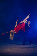 gymnast girl aerial acrobatics on the ring on the background of blue smoke in the dark